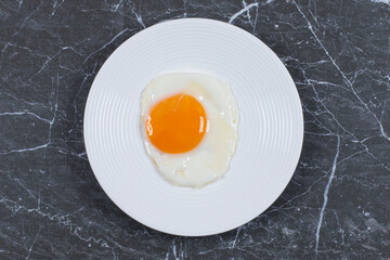 Delicious fried egg on the plate , on the marble background