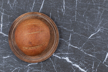 A single loaf on the board, on the marble background