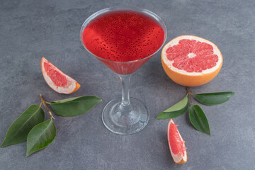 A glass cup with red juice and slices of grapefruit