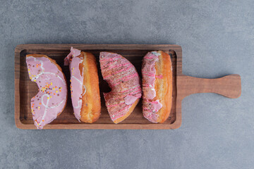 Chopped cake with pink frosting on a wooden board