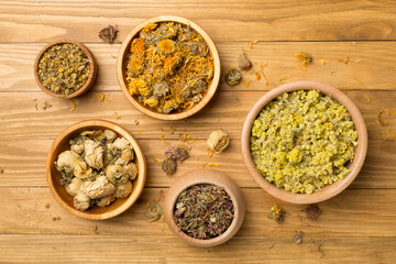 Different herbs in bowls on wooden background, top view