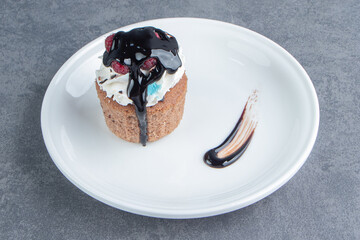 A white plate with delicious creamy cupcake on a gray background