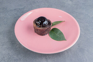 A piece of chocolate cake with leaves on a pink plate