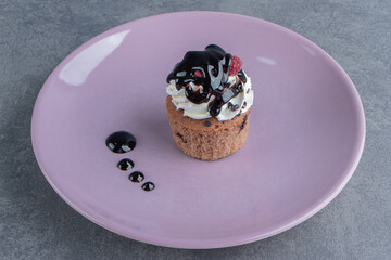 Sweet creamy cupcake on a purple plate