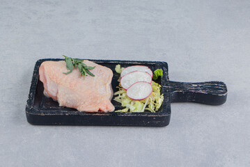 Raw chicken breasts and spices on the board, on the white background