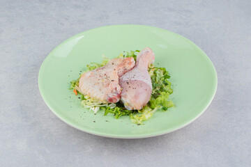 Two marinated chicken legs in the plate, on the white background
