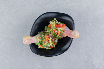 Raw chicken legs with spices in the bowl , on the blue background