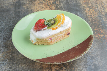 A delicious eclair with fruits on a green plate