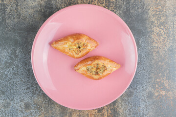A pink plate with two home made triangle pies