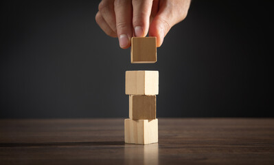 Male hand stacking wooden empty cubes.