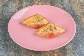 A pink plate with two home made triangle pies