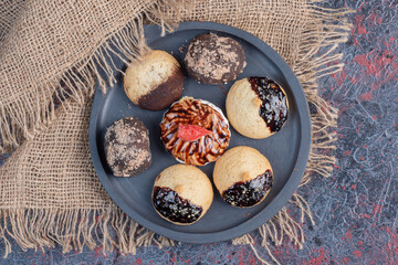 Different sweet cookies on black plate