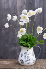 White spring anemones in vase on wooden background
