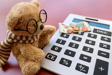 Fotobehang Small teddy bear in eyeglasses using calculator for calculating money  © Olga