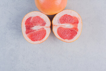 Half cut and whole grapefruit on grey background