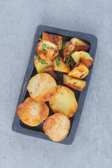 Fried potato slices in black bowl