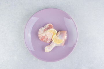 Lemon and chicken meat in the plate, on the marble background
