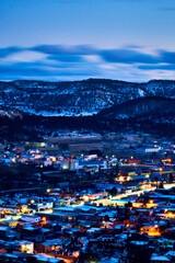 village on winter with snow in the mountains and sky in blue hour, lights on the houses and streets, aereal view from creel chihuahua 