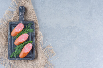 Fresh salami with fennel leaves on black cutting board