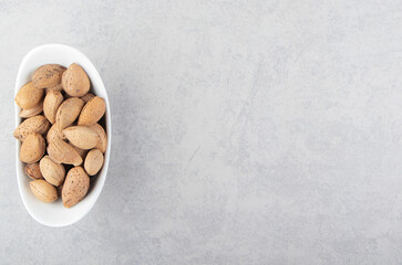 Almonds in the white bowl, on the marble background