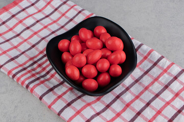 Red candies in the bowel on the towel on the marble background