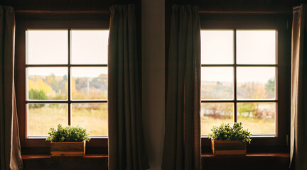 Two country house windows with a windowsill flowers pots showing a countryside landscape. Geometrical indoor concept.