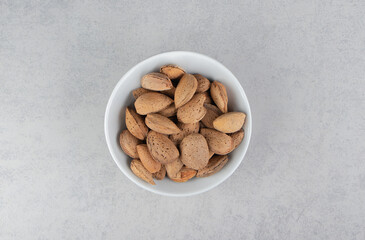 Flavorful almonds in the bowl, on the marble background
