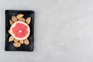 Grapefruit and almonds on the board, on the marble background