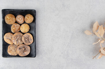 Leaves and dried fig on the board, on the marble background