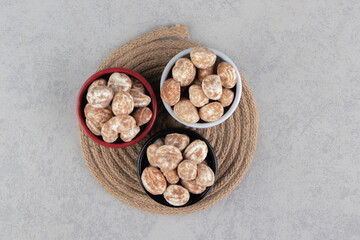 Three bowl of cinnamon cookies on the trivet, on the marble background
