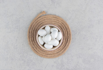 White candies in the cup on the trivet, on the marble background