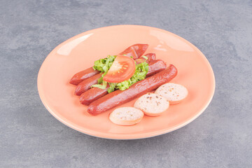 Whole sausages and sliced sausages on the plate , on the marble background