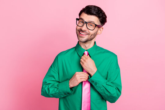 Photo of cheerful positive guy wear green shirt spectacles adjusting tie isolated pink color background