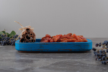 Grape, cinnamon and dried fruit in the bowl, on the marble background