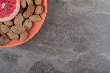 Grapefruit and almonds on the plate on the marble background