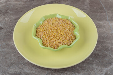 A bowl of bulgur on the plate ,on the marble background