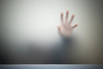 Male hand behind gray blurred matte glass wall