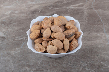 Delicious almonds in the bowl, on the marble background
