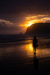silhouette of a beautiful woman in a long dress with a colourful sunset on a tropical beach in the...