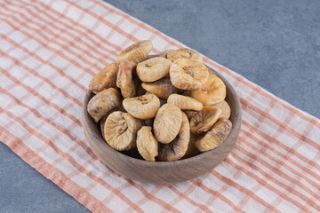 Tasty dried fruits in bowl on the towel, on the marble background