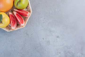 A small bundle of fruits in a white basket on marble background