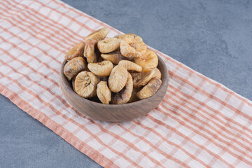 Tasty dried fruits in bowl on the towel, on the marble background