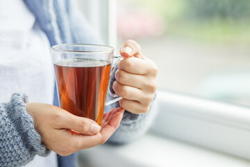 Cup of hot tea in female hands close-up. Background. Beverage concept, lifestyle, autumn and winter.