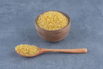 A spoonful of rice and a bowl of rice , on the marble background