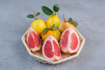 Pears and grapefruit slices in a white basket on marble background