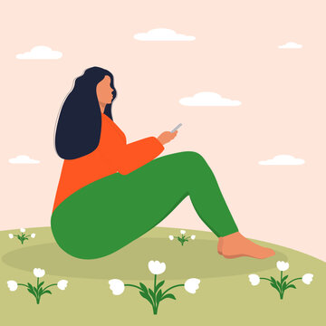 Young woman sits on a flower meadow.