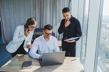 Group of business people in casual clothes talking to each other in office and using gadgets while working on business startup in modern workspace
