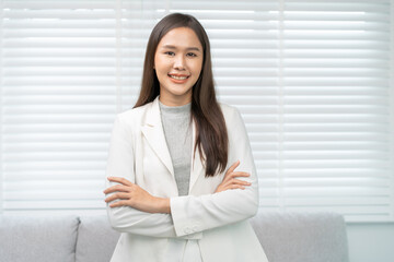 Smiling positive, attractive asian young woman wearing suit, standing with arms crossed at office portrait elegant person long brunette hair, feeling happy looking camera, isolated on white background