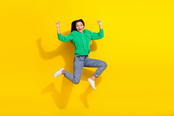 Fototapeta na wymiar Full size photo of sporty young lady jumping raise fists marathon winner wear stylish green sportswear isolated on yellow color background