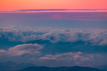 Naklejka na ściany i meble Panoramic view form mountains peak on the fog and clouds. Sunrise landscape.